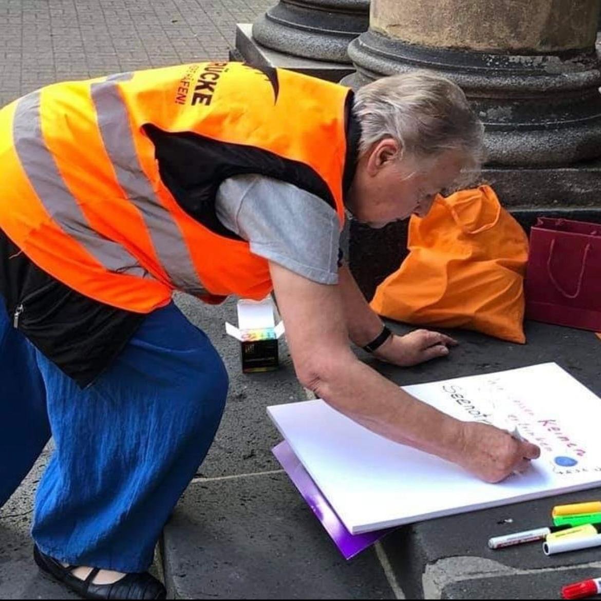 Teilnehmerin gestaltet ein Plakat bei einer Seebrücke-Aktion